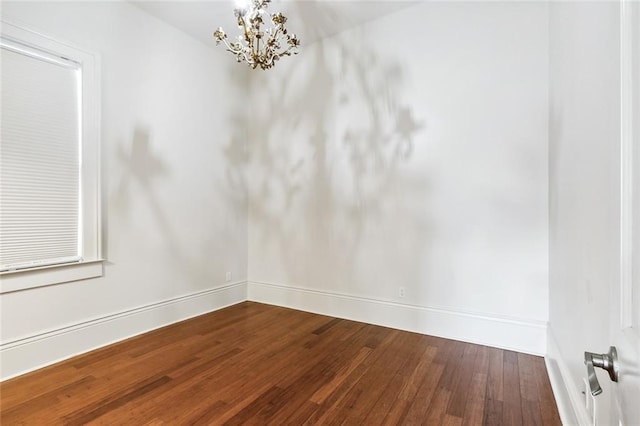 empty room featuring hardwood / wood-style flooring and an inviting chandelier