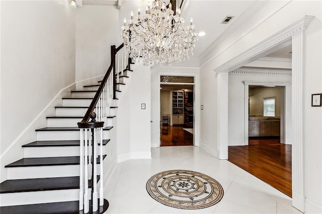 foyer with tile patterned flooring, crown molding, and a chandelier