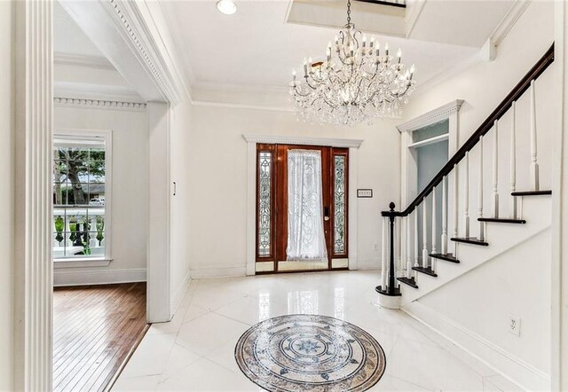 entryway with an inviting chandelier and ornamental molding