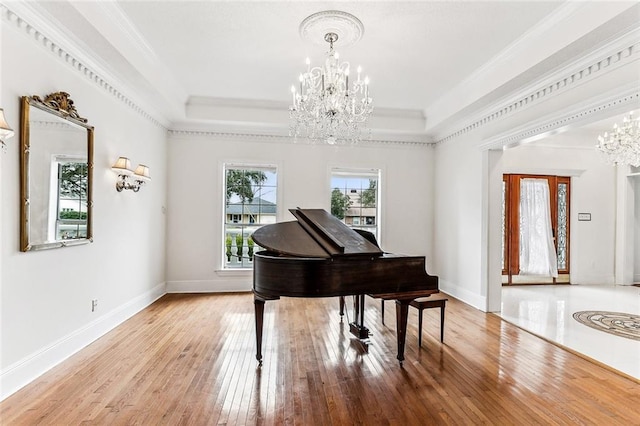 miscellaneous room with hardwood / wood-style flooring, a tray ceiling, crown molding, and a chandelier