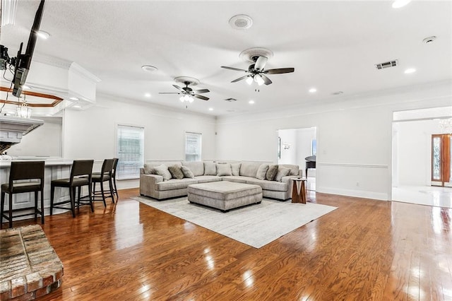 living room featuring a brick fireplace, ceiling fan, hardwood / wood-style flooring, and crown molding