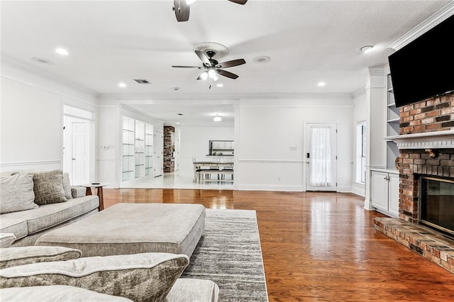 living room with a fireplace, light wood-type flooring, and crown molding