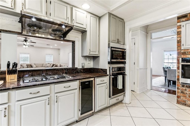 kitchen with dark stone countertops, beverage cooler, crown molding, appliances with stainless steel finishes, and ceiling fan