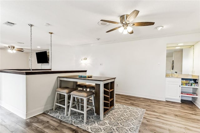 kitchen featuring white cabinetry, ceiling fan, kitchen peninsula, wood-type flooring, and pendant lighting