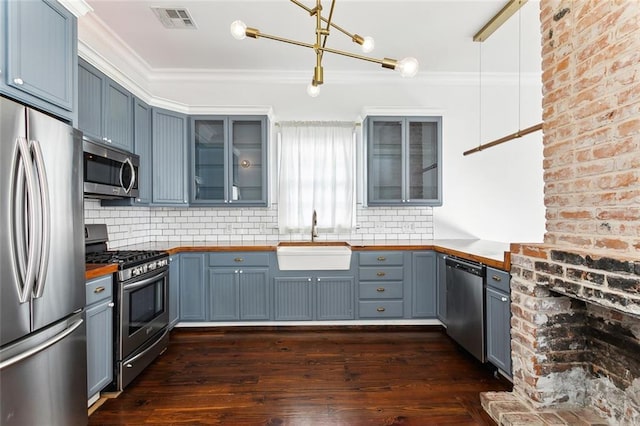 kitchen featuring sink, hanging light fixtures, dark hardwood / wood-style flooring, a chandelier, and appliances with stainless steel finishes