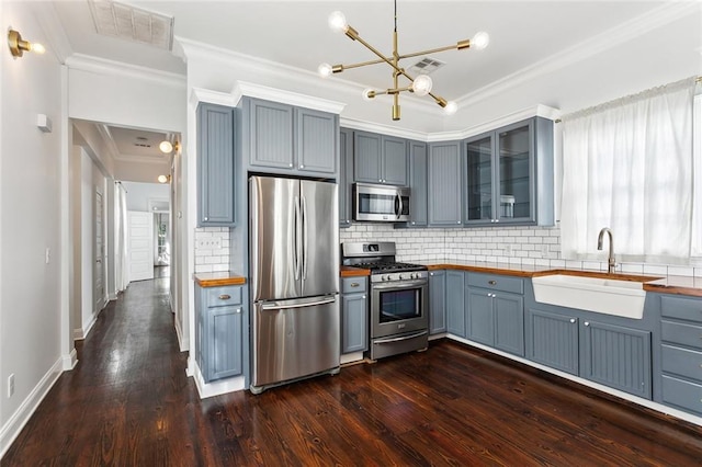 kitchen featuring decorative backsplash, dark hardwood / wood-style flooring, stainless steel appliances, crown molding, and sink