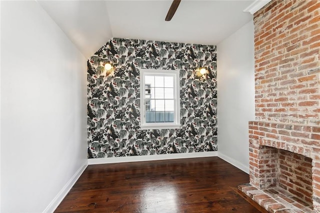 unfurnished room featuring lofted ceiling, a fireplace, and dark hardwood / wood-style floors