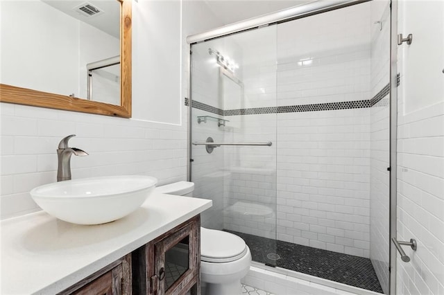 bathroom featuring vanity, toilet, tile walls, and a shower with shower door