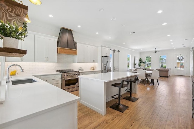 kitchen with appliances with stainless steel finishes, a kitchen island, a barn door, and white cabinetry