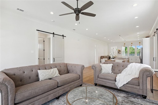 living room featuring a barn door, crown molding, and hardwood / wood-style floors