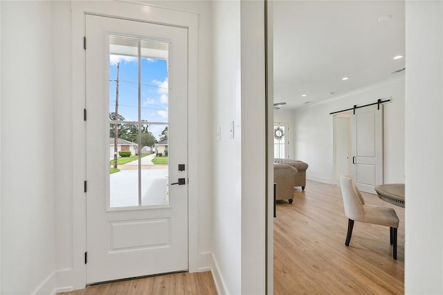 doorway to outside with light hardwood / wood-style floors and a barn door