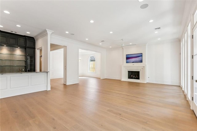 unfurnished living room with light hardwood / wood-style floors and crown molding