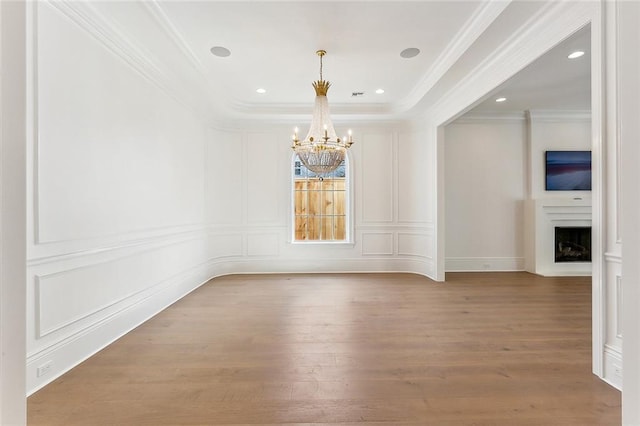 empty room with hardwood / wood-style floors, an inviting chandelier, and crown molding