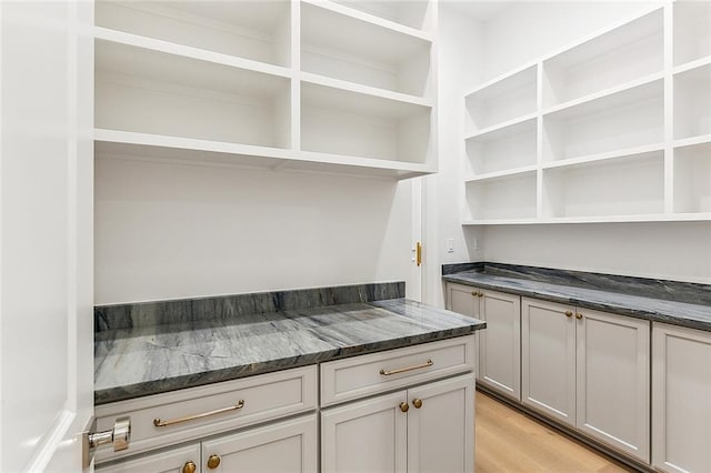 kitchen with light hardwood / wood-style floors, gray cabinetry, and dark stone countertops