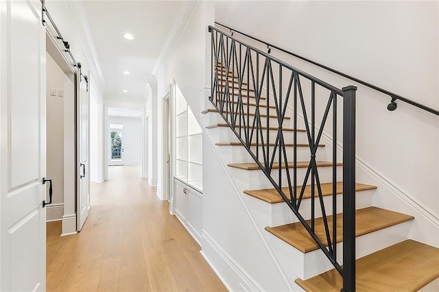 stairs featuring a barn door, crown molding, and hardwood / wood-style flooring