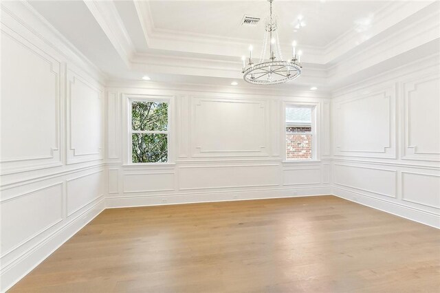 interior space with a tray ceiling, crown molding, light hardwood / wood-style flooring, and a notable chandelier