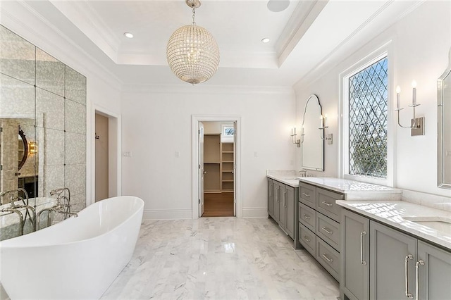 bathroom with a raised ceiling, a tub to relax in, crown molding, a fireplace, and vanity