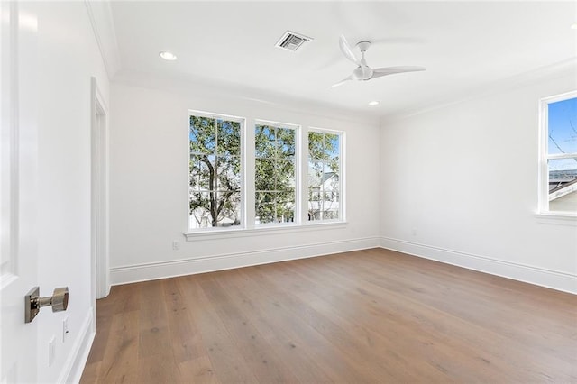 empty room featuring plenty of natural light, hardwood / wood-style floors, and ornamental molding