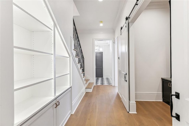 hall featuring light wood-type flooring, a barn door, and crown molding