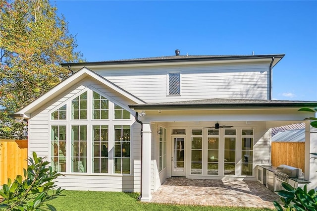 back of property with ceiling fan, a patio area, a yard, and an outdoor kitchen