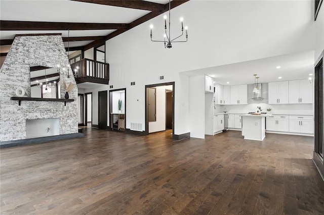 unfurnished living room featuring a towering ceiling, beamed ceiling, dark hardwood / wood-style floors, and a notable chandelier