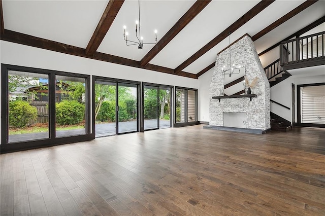 unfurnished living room with hardwood / wood-style floors, a stone fireplace, high vaulted ceiling, and an inviting chandelier