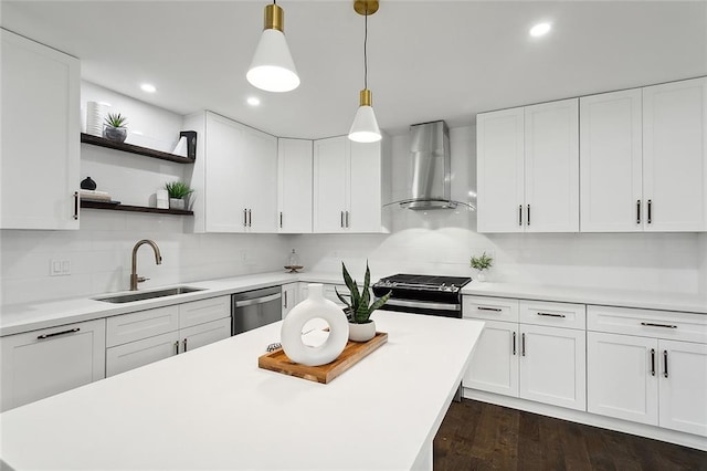 kitchen featuring stainless steel appliances, sink, wall chimney range hood, decorative light fixtures, and white cabinetry