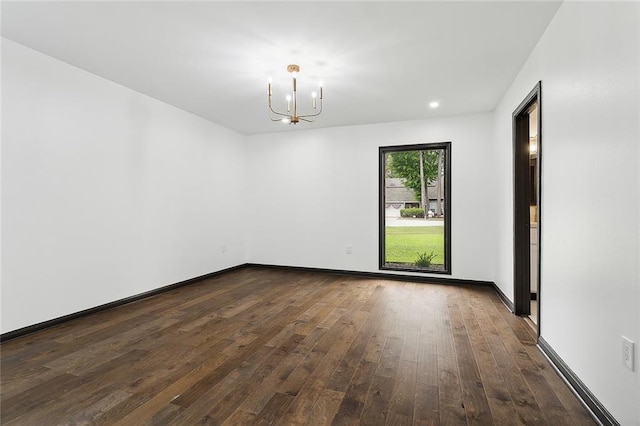 spare room with dark hardwood / wood-style floors and a notable chandelier