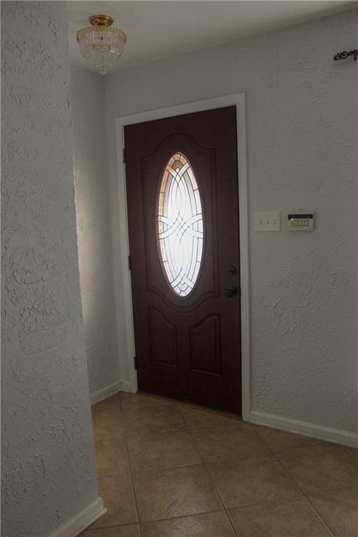 tiled entrance foyer with an inviting chandelier