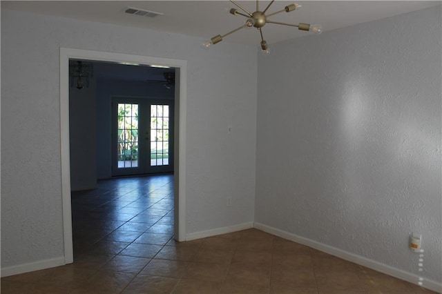 empty room with french doors, a notable chandelier, and tile patterned flooring