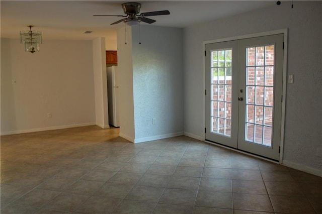 empty room featuring french doors, light tile patterned floors, and ceiling fan with notable chandelier