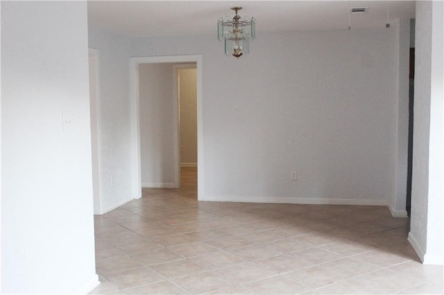 spare room featuring a chandelier and light tile patterned floors