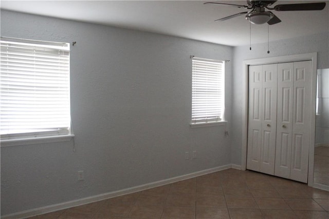 unfurnished bedroom featuring a closet, dark tile patterned flooring, and ceiling fan