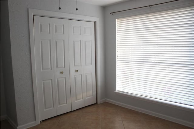 unfurnished bedroom featuring multiple windows, a closet, and light tile patterned floors