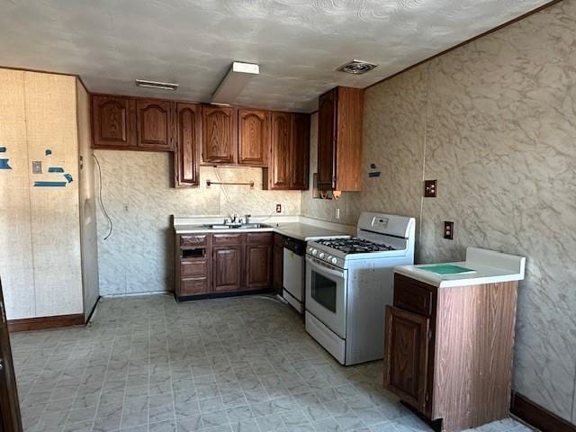 kitchen featuring dishwasher, a textured ceiling, white gas range, and sink