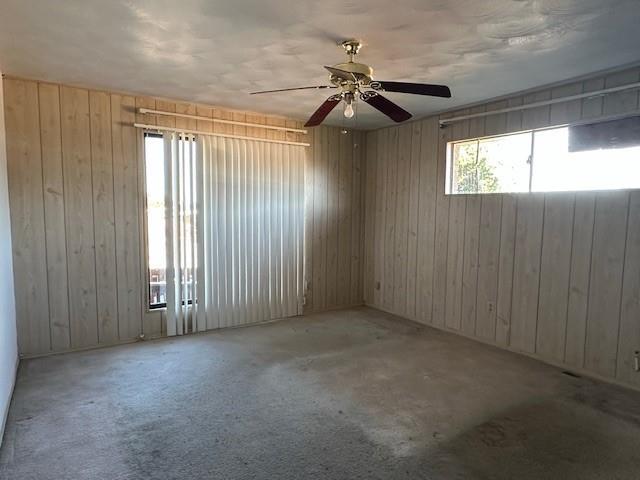 unfurnished room featuring wooden walls and ceiling fan