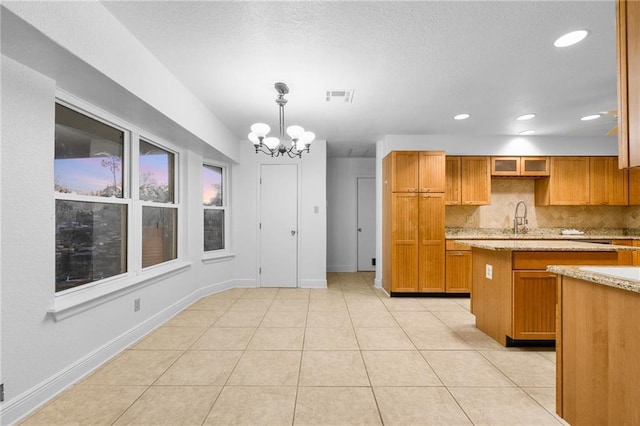 34222 Laurent Rd, Slidell, LA 70460 - kitchen with tasteful backsplash, a chandelier, brown cabinetry, decorative light fixtures, and light tile patterned floors