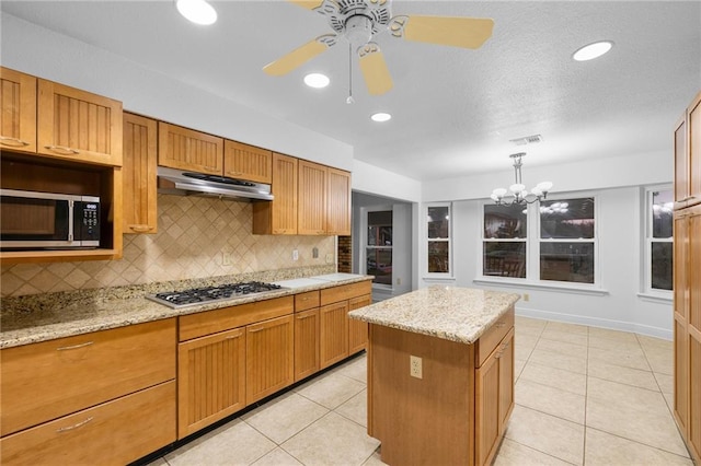 kitchen with decorative backsplash, a center island, stainless steel appliances, and light stone counters