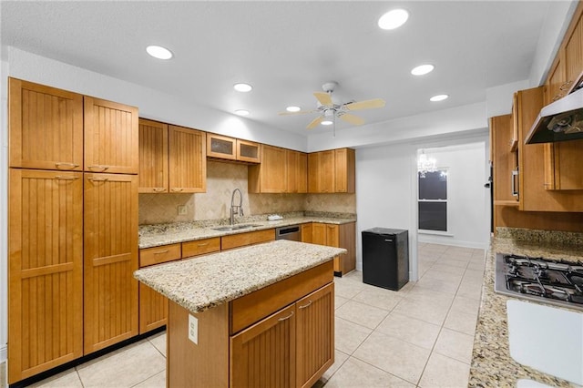 kitchen featuring sink, ceiling fan, decorative backsplash, light stone countertops, and a kitchen island