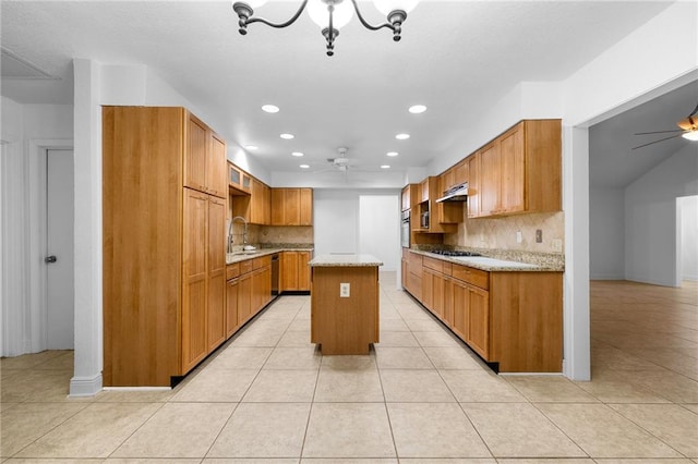 kitchen featuring backsplash, ceiling fan with notable chandelier, a center island, and sink