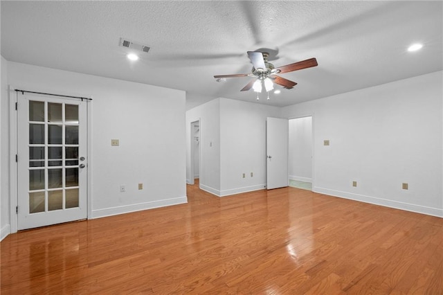 unfurnished room with ceiling fan, light wood-type flooring, and a textured ceiling