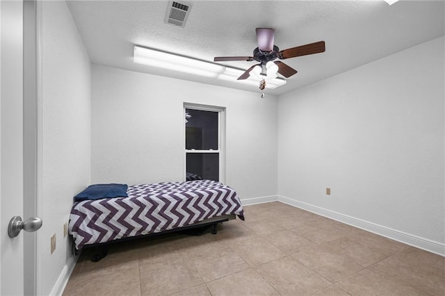 bedroom with ceiling fan, light tile patterned flooring, and a textured ceiling