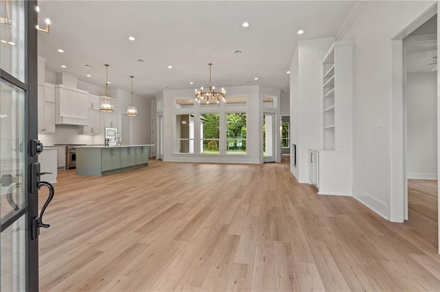 unfurnished living room with light wood-type flooring and a chandelier