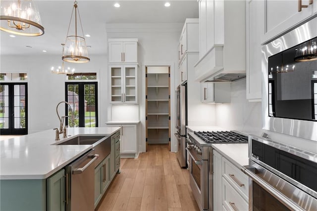 kitchen with premium appliances, white cabinetry, an island with sink, and french doors