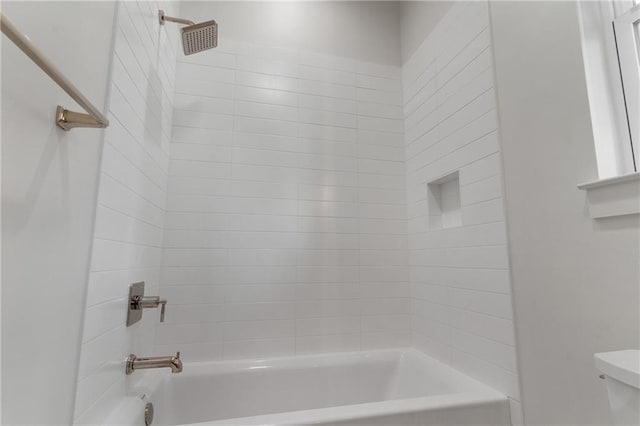 bathroom with tiled shower / bath combo and toilet