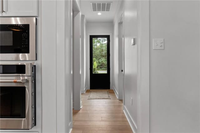 entryway with light hardwood / wood-style floors and ornamental molding