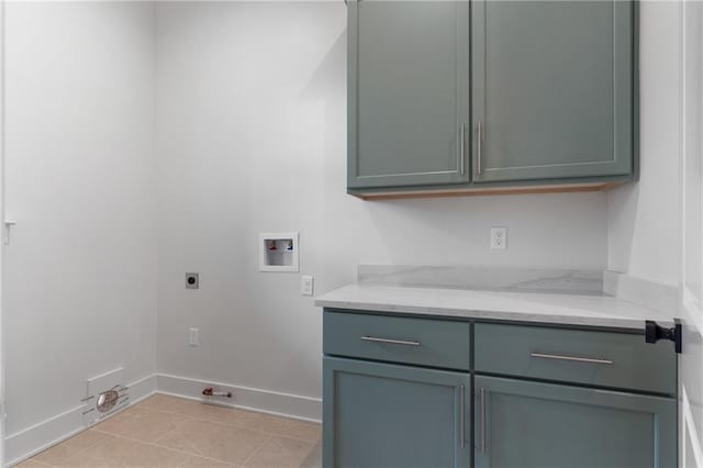 clothes washing area featuring electric dryer hookup, cabinets, gas dryer hookup, washer hookup, and light tile patterned floors