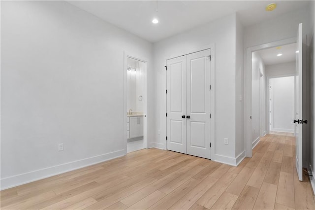 interior space with ensuite bath, a closet, and light hardwood / wood-style flooring