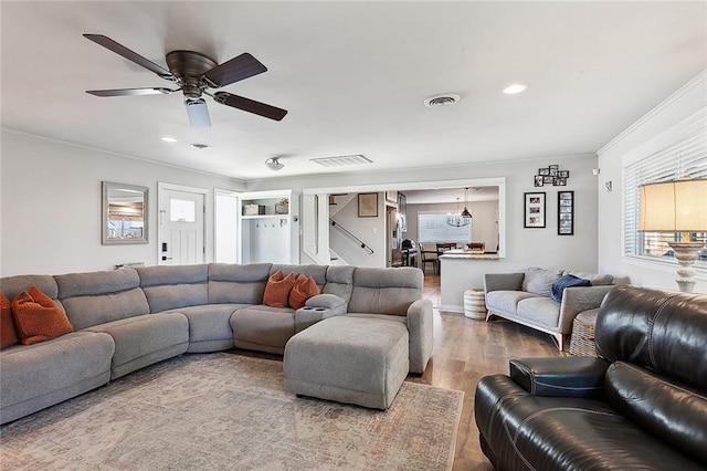 living room featuring ceiling fan, wood-type flooring, and ornamental molding