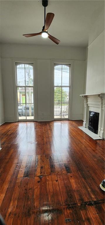 unfurnished living room featuring hardwood / wood-style floors, ceiling fan, and a healthy amount of sunlight